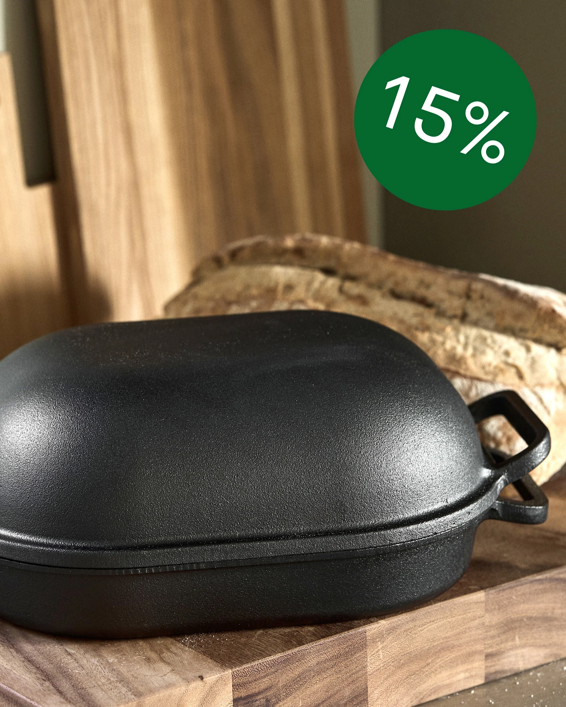 Black cast iron bread pot on wooden cutting boards with a baked loaf and a green 15% off sticker.
