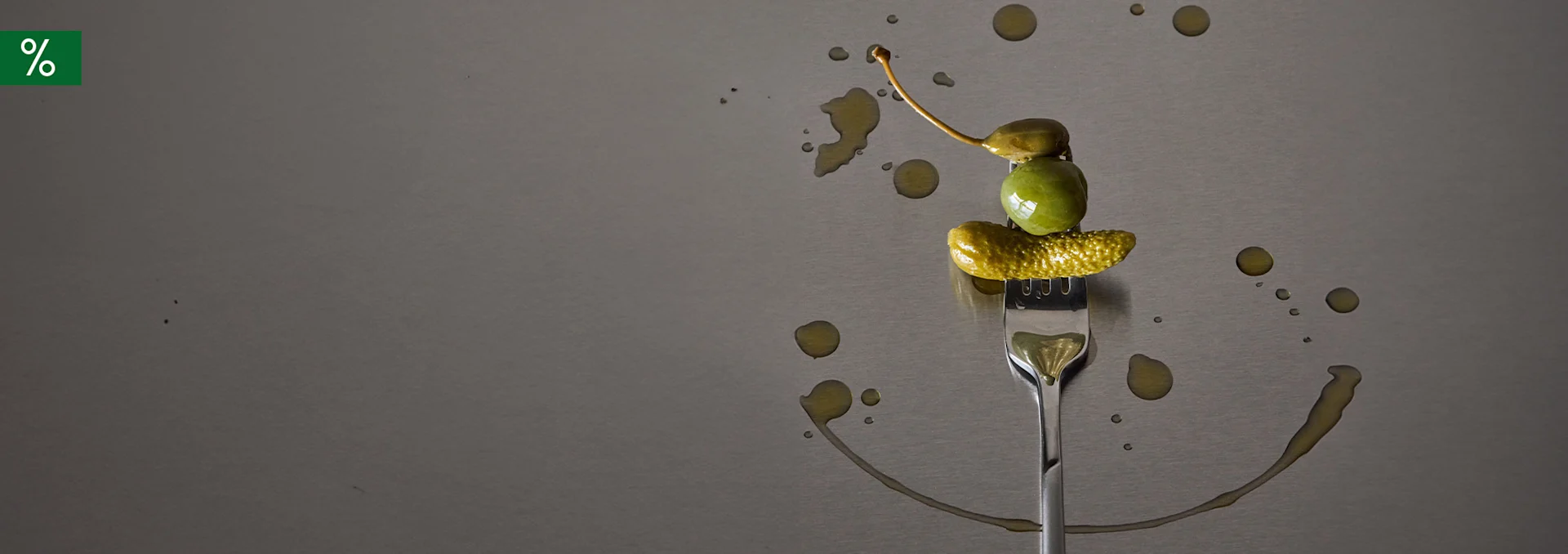 Green caper, olive, and gherkin on a fork; oil drops form a smiley face; green percent box.