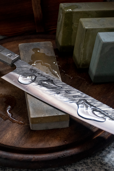 A Japanese knife is hand sharpened on a whetstone. 